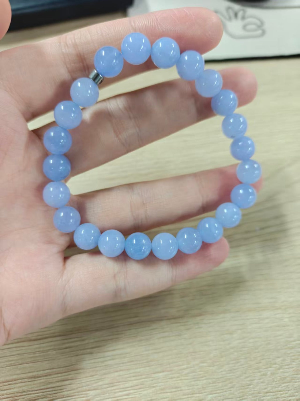 Bracelet en pierre naturelle bleue translucide tenu en main