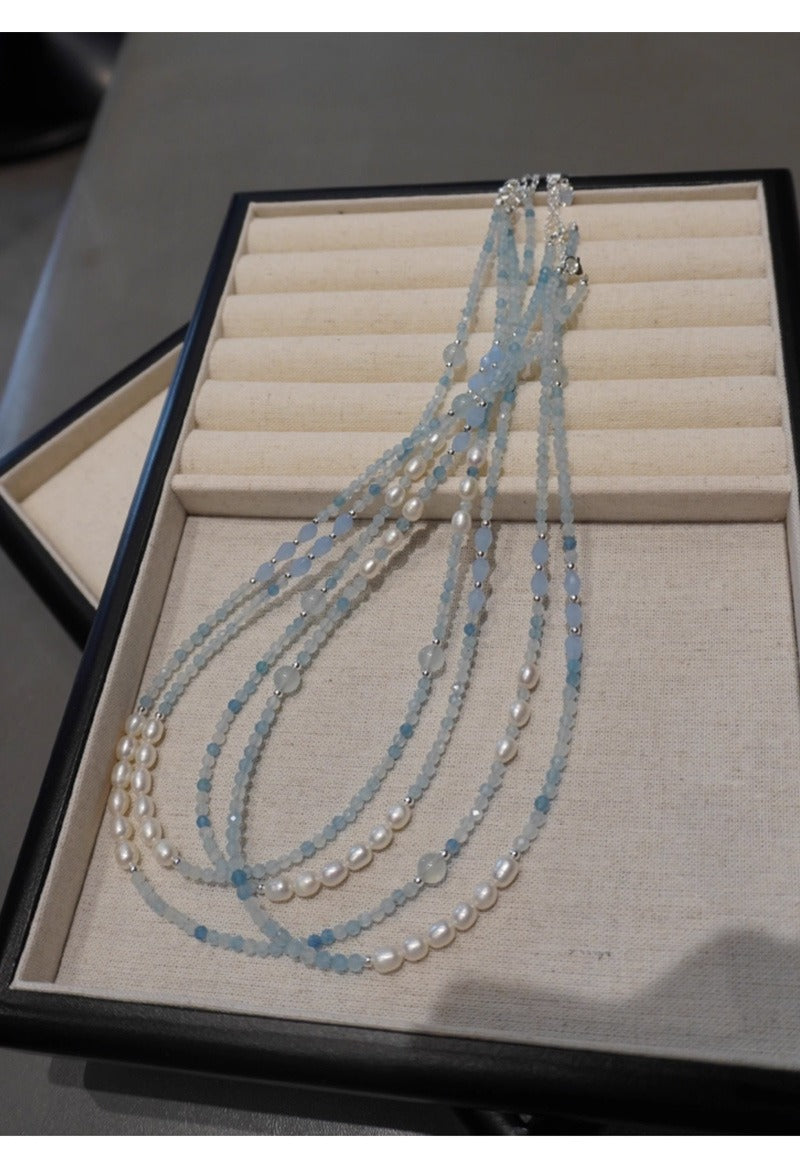Colliers en aigue-marine et perles d'eau douce sur présentoir à bijoux