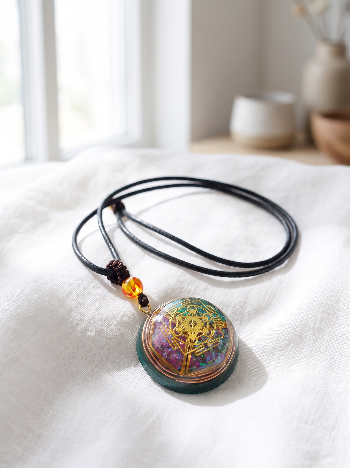 Collier orgonite posé sur lin blanc, cordon noir naturel