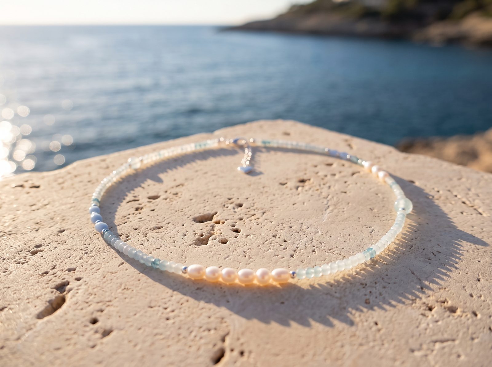 Collier « Douceur de la Mer » posé sur une pierre au bord de la mer